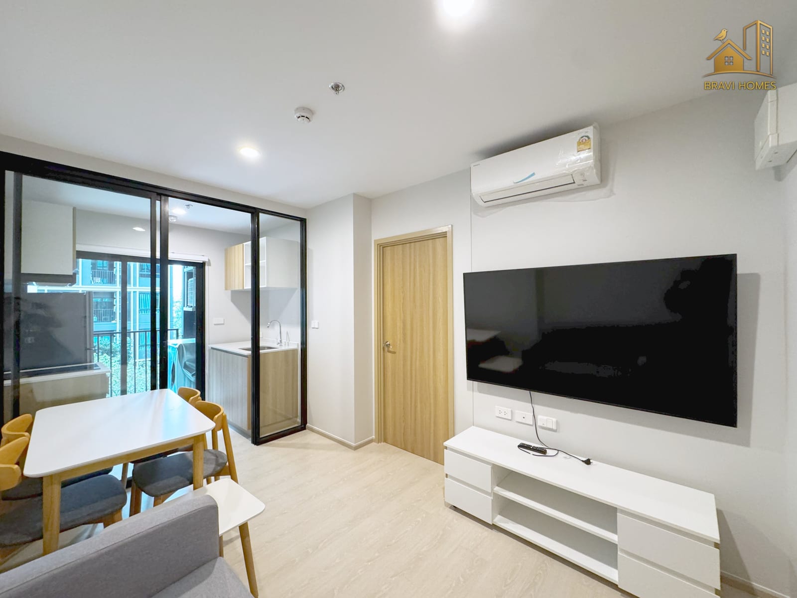 NUE CONNEX ดอนเมือง ห้องนั่งเล่นมองจากโซฟา ทีวีจอใหญ่และโต๊ะทานอาหาร