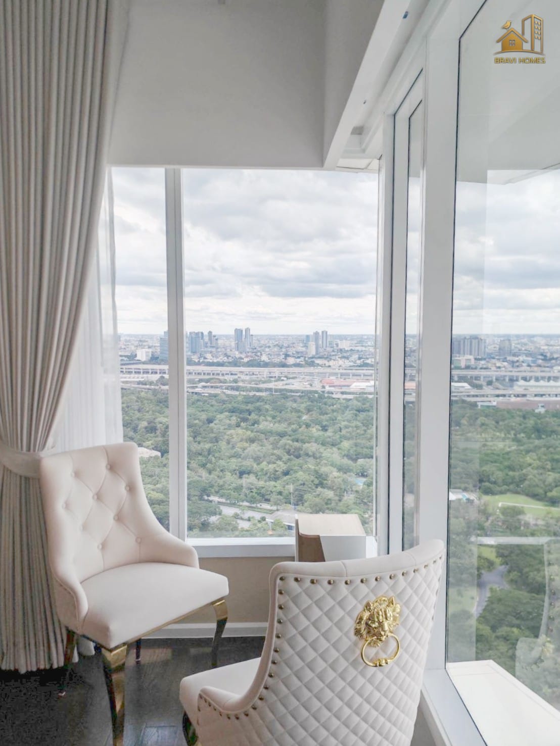 The Saint Residences 2 นอน 2 น้ำ 70.2 ตร.ม. มุมนั่งเล่นริมหน้าต่างในห้องนอน เก้าอี้บุนวมและวิวสวน